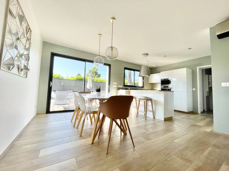 Pièce à vivre ouverte : table à manger, cuisine et baie vitrée sur la terrasse